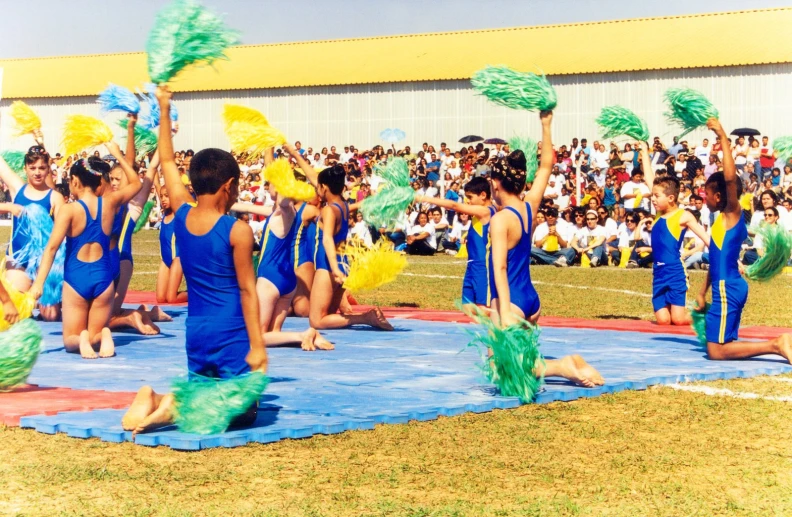 many people in blue costumes and pom poms performing with a crowd watching