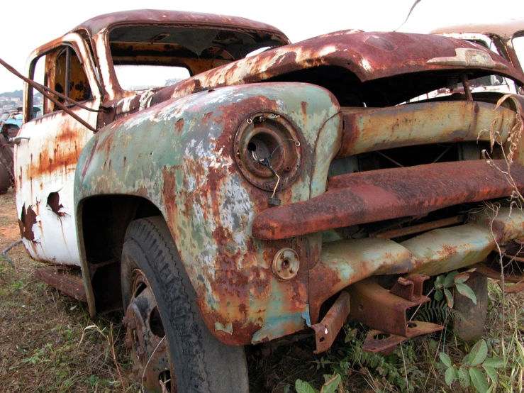 an old, rusted truck sits in a field