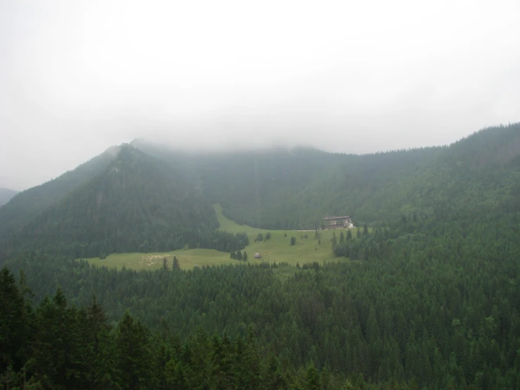 mountains, with a few trees in front of them and houses on a hill