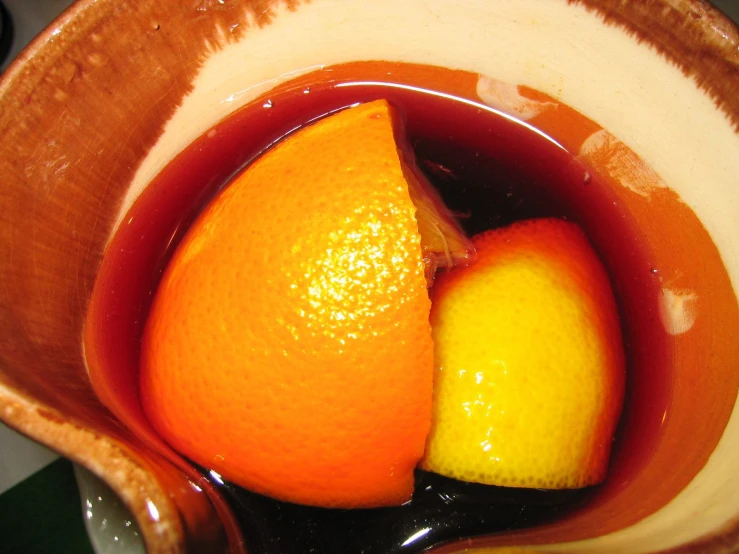 an orange sits inside of a pitcher of liquid