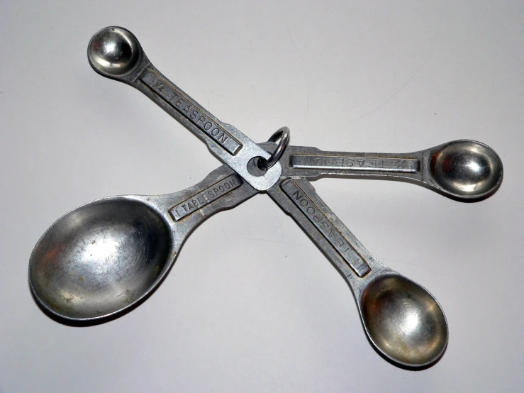 four silver colored serving utensils sitting on a table