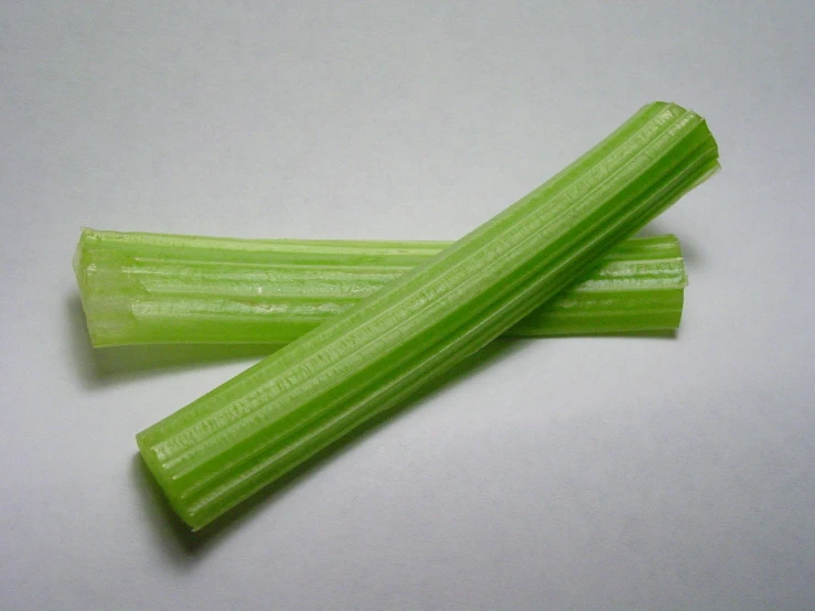 two thin, thin pieces of celery sit on a white surface