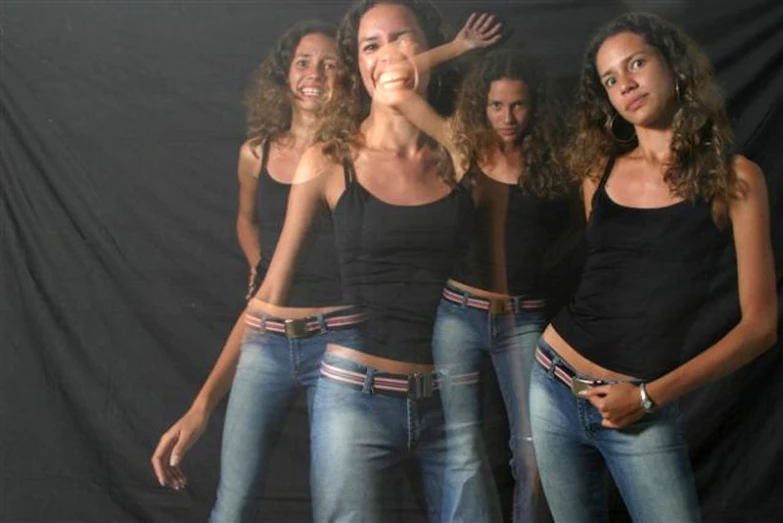 four girls are posing together on the black background