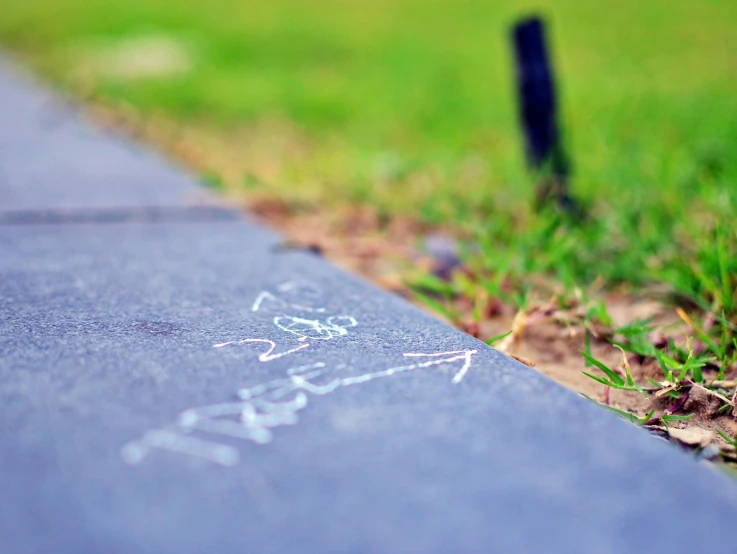 a sidewalk is covered with a graffiti in the grass