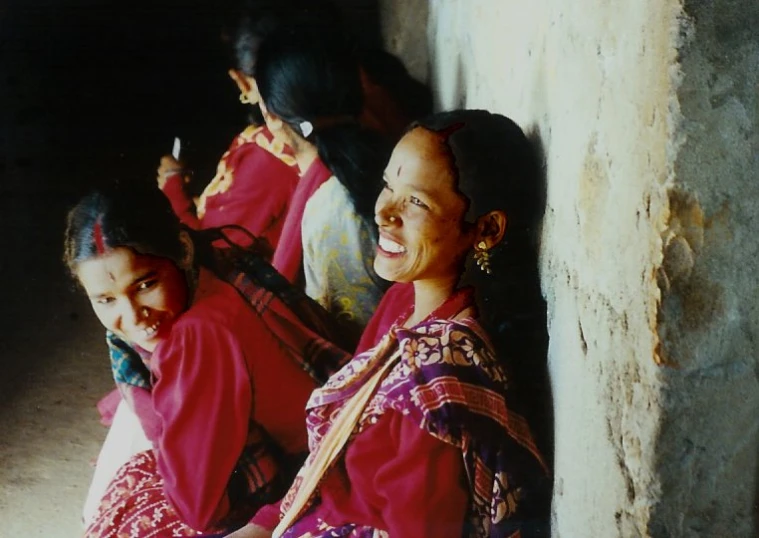 women in bright clothes are sitting on the wall