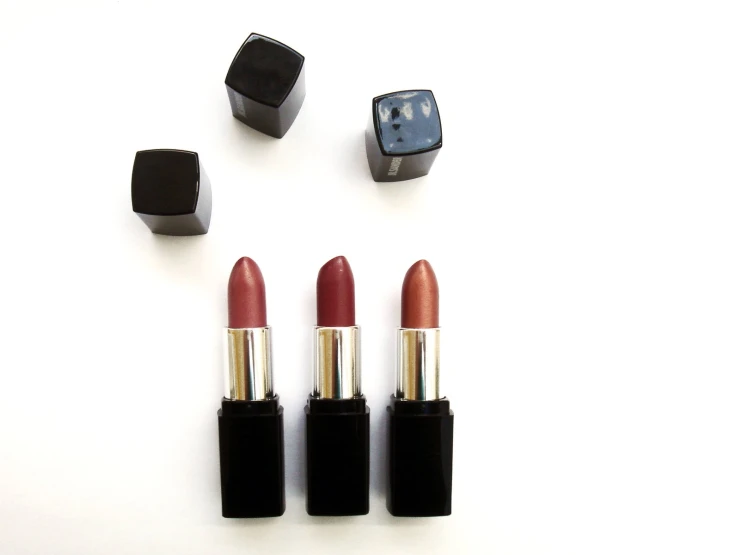 three lipsticks sitting on top of each other on a white table