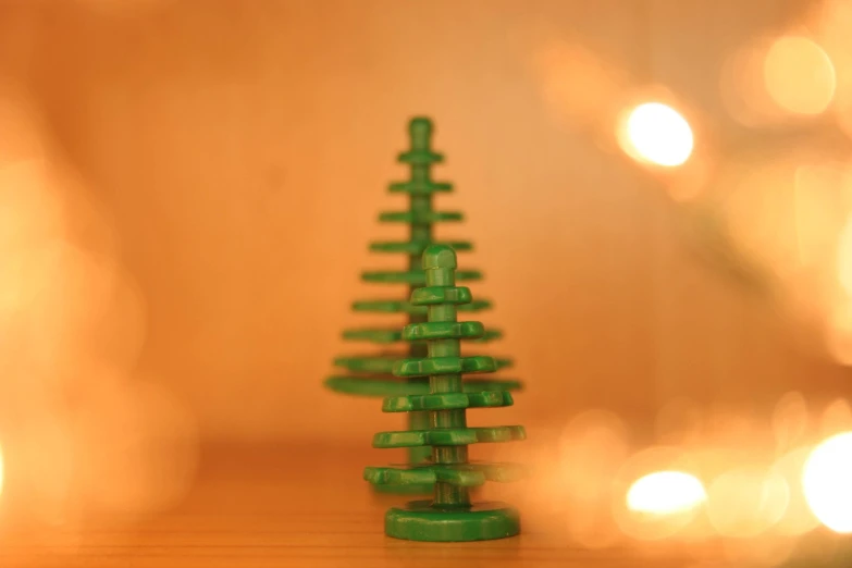 small green object with holes in the middle and a white string tree standing out in front