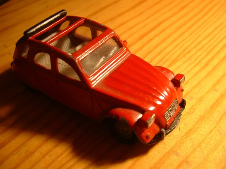 the toy car is on the wooden surface