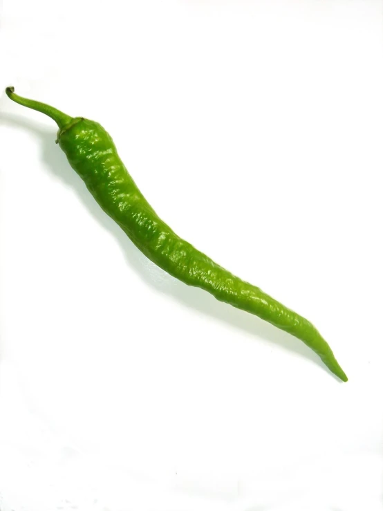 a green pepper sits in the middle of a white surface