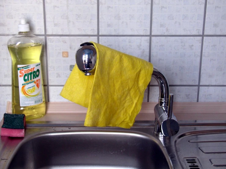 a yellow towel, cleaner's bottle, and other cleaning supplies sitting on a kitchen counter