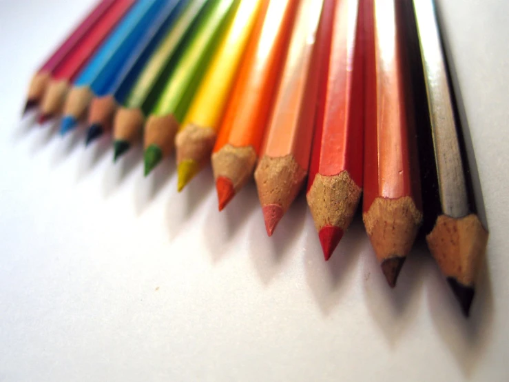 colorful pencils lined up in different colors on a surface