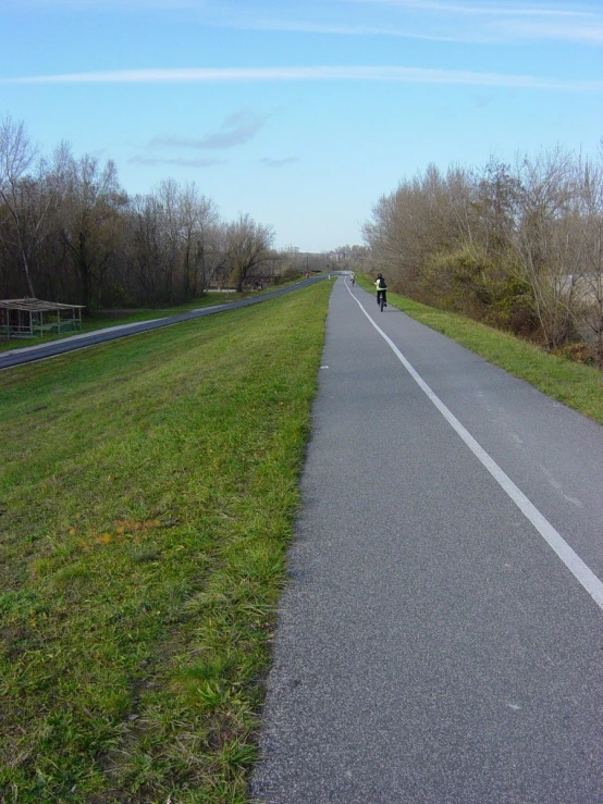 person riding on a bicycle down an asphalt path