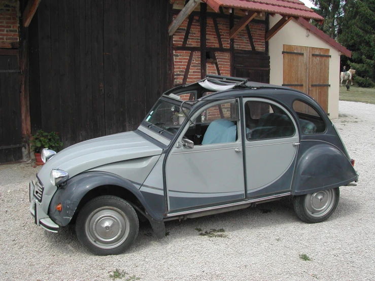 the old grey and black car is parked near a building