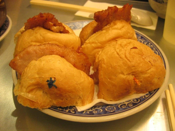 three pastries are on a plate with chopsticks next to them