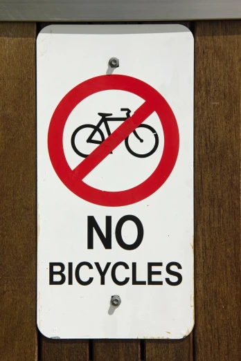 a no bicycle sign sitting on the side of a fence