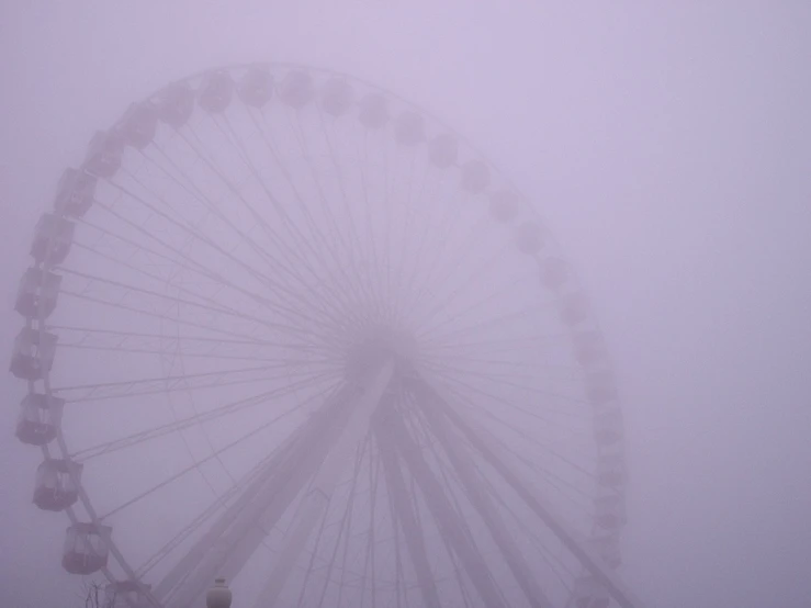 the ferris wheel is covered in fog and sleet