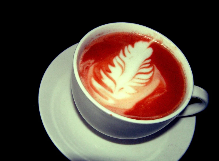 a cup of red liquid with white leaf designs