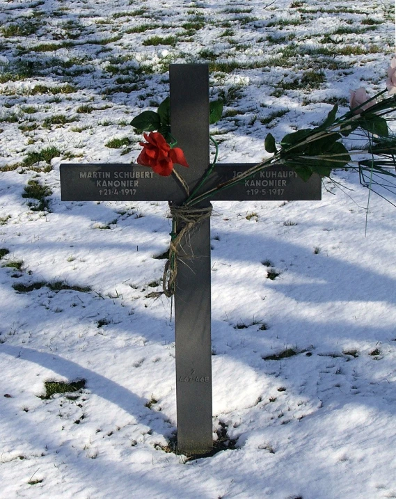 a cross with flowers on it, on snow covered ground