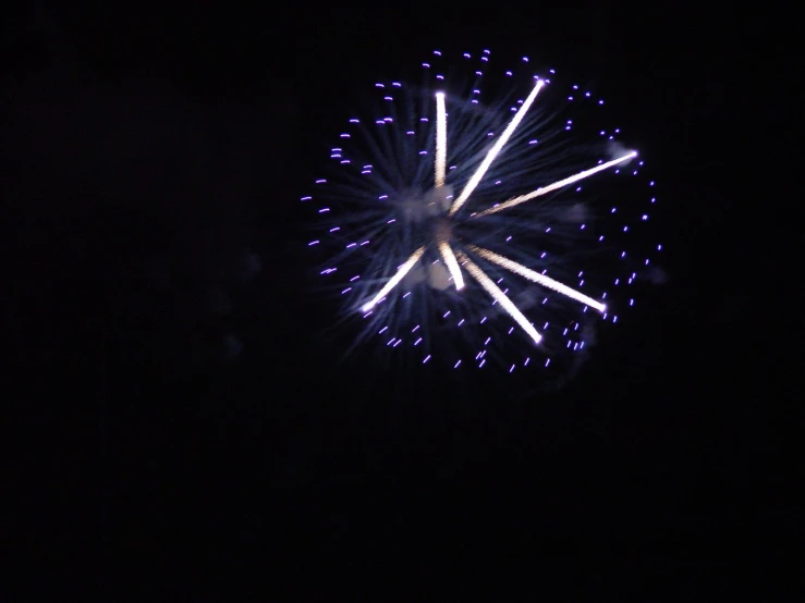 fireworks explode as people watch them in the dark