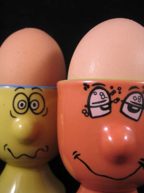 two egg cups painted with funny faces and faces