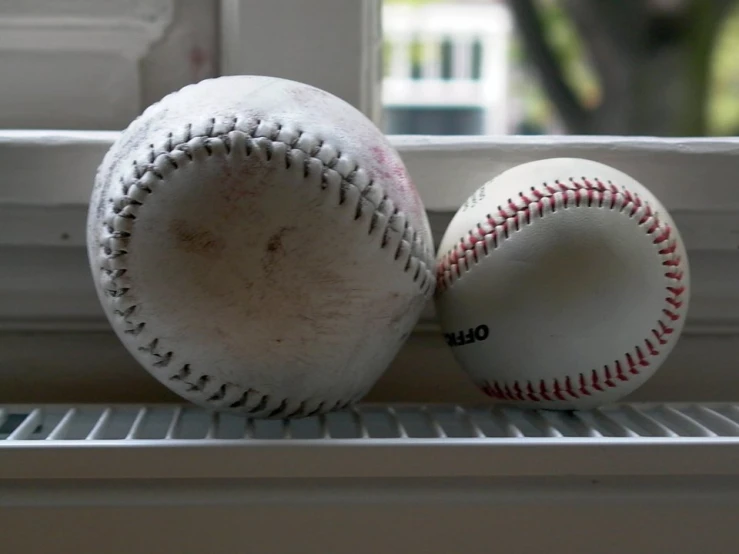 a pair of baseballs sitting on top of an old refrigerator