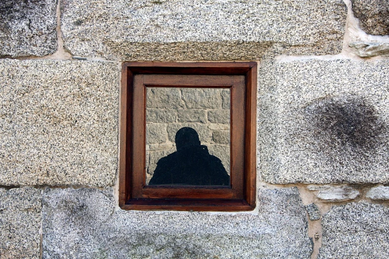 a reflection in the window of a stone wall