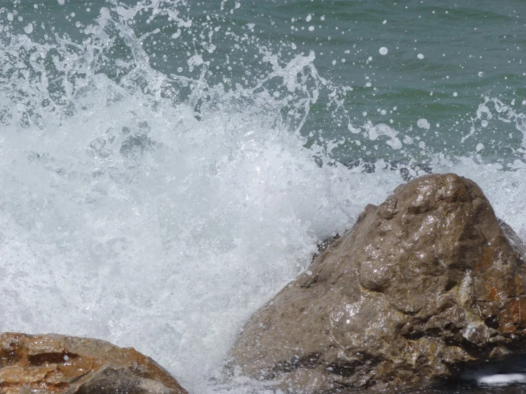 there is a wave crashing on a rock