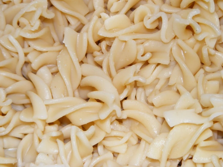 noodles are being stirred in white sauce for consumption