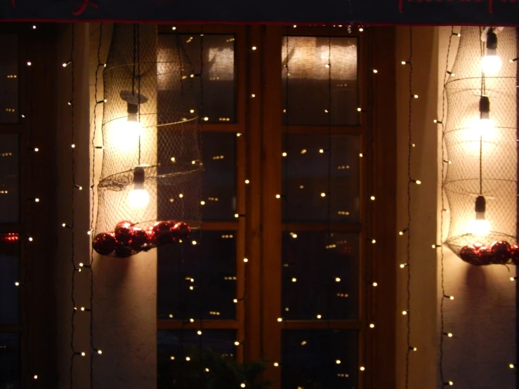 two decorative lighted windows covered in curtain with light strings hanging down the side