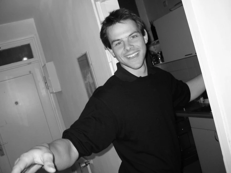 a man posing in a home kitchen with his hand on the edge of the cabinet