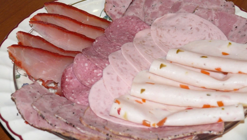 ham on plate with pieces of sausage and pepper