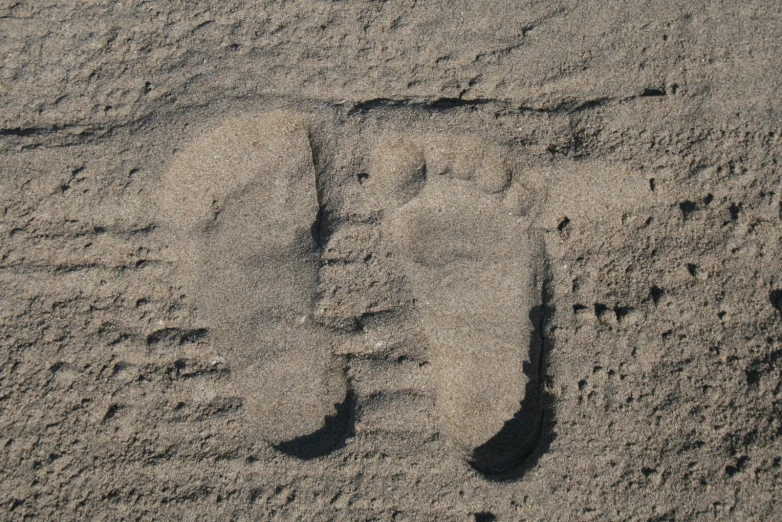 footprints in the sand with two shoes drawn