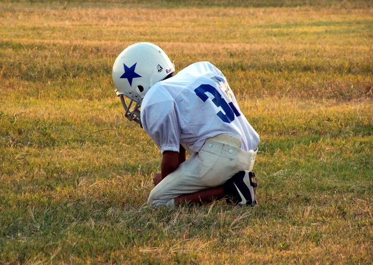 a football player kneels down to his side