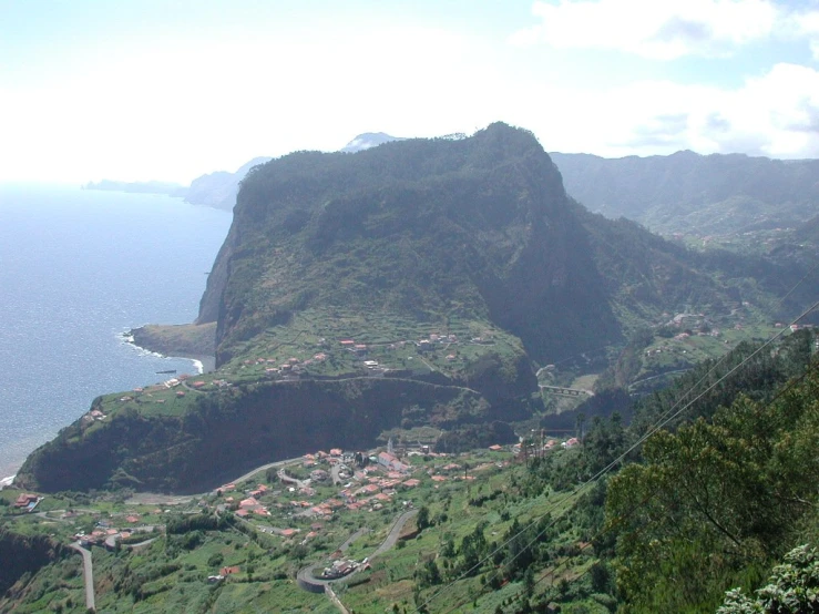 two people on a cliff look down at the town below