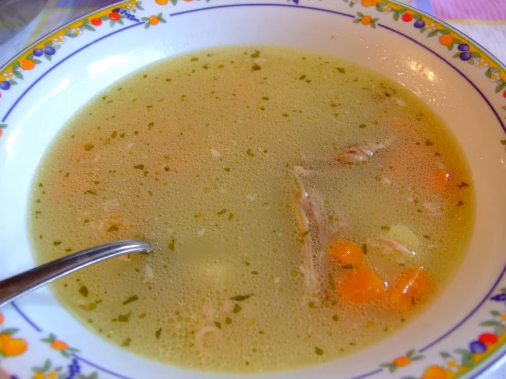 a bowl filled with chicken and vegetables next to a spoon