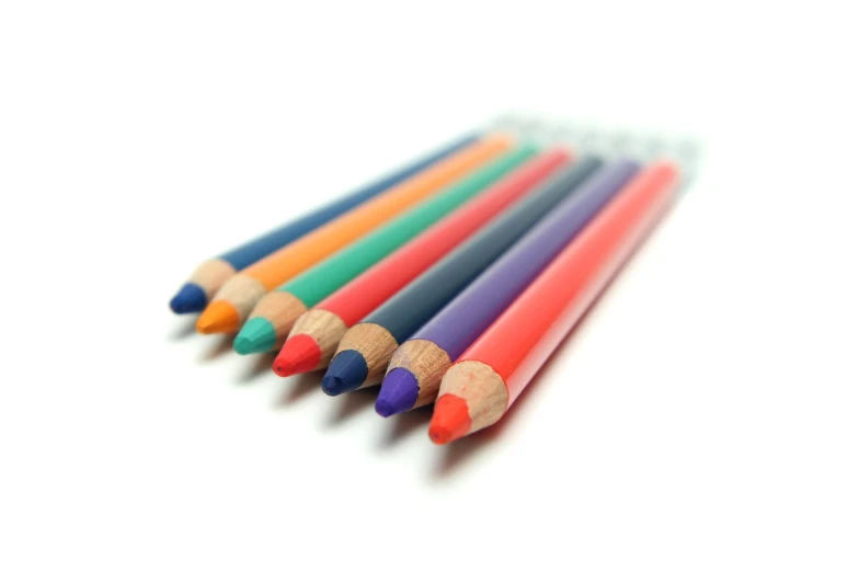 six colored pencils sitting on a white surface