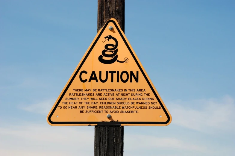 warning sign on wooden pole stating caution