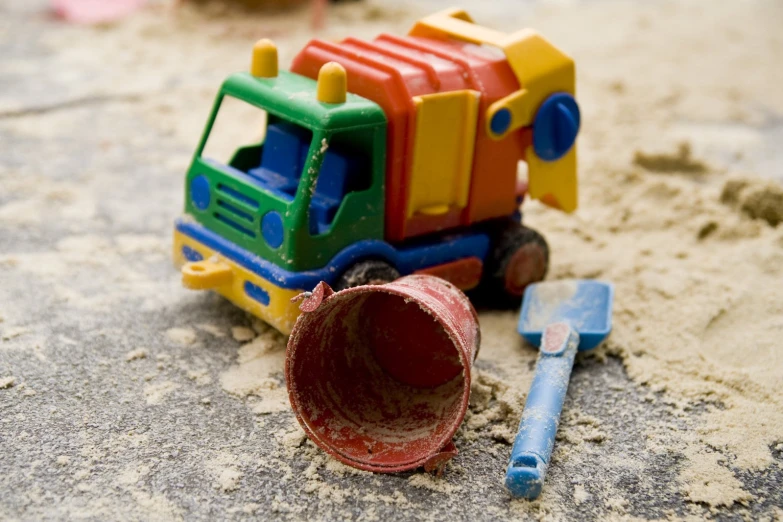 a toy car sitting in the sand with a wrench