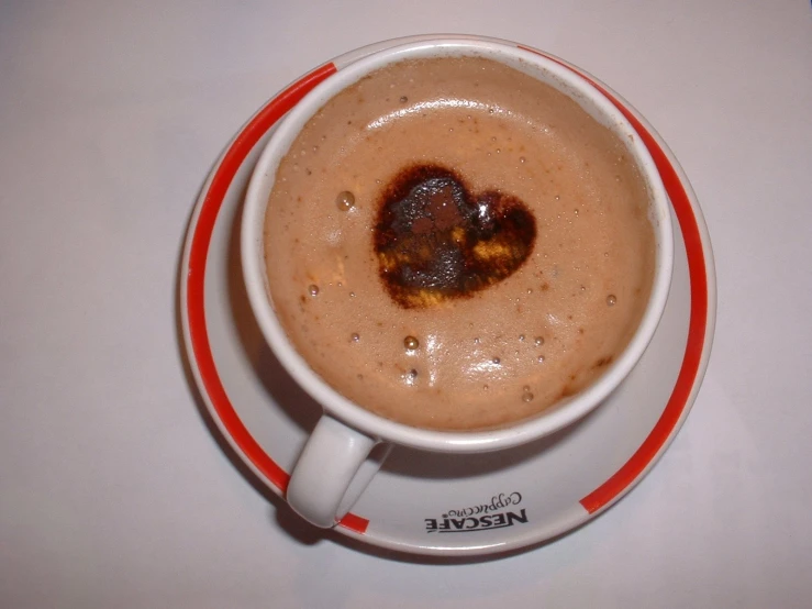 a white cup with a saucer with brown liquid