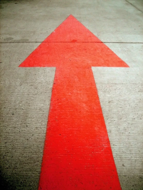 a red arrow drawn on the sidewalk and pavement