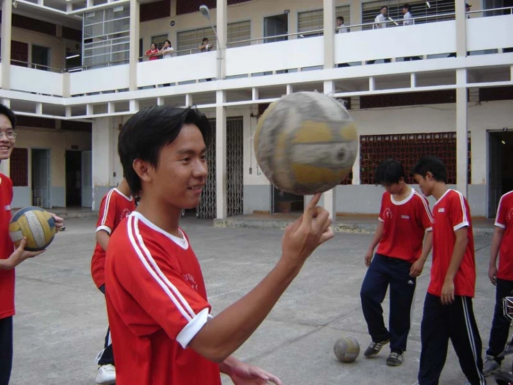 young men in red shirts are holding up soccer balls