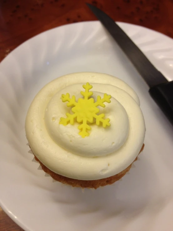 a cupcake on a white plate with yellow snowflakes