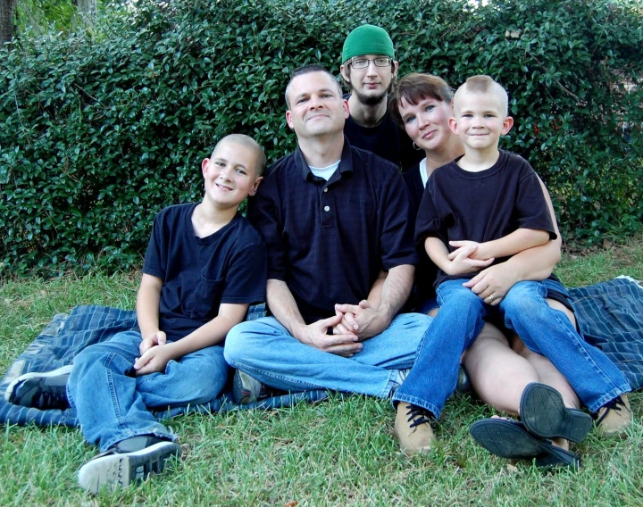 the group of people are in a circle in front of bushes