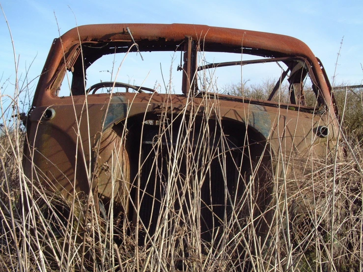 an old rusted pickup truck sitting in tall grass