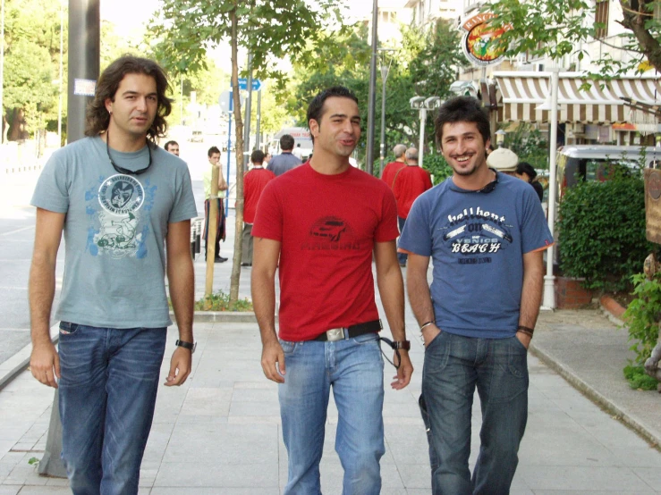 three young men standing on the side walk