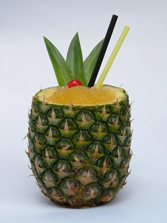 a pineapple is garnished with orange juice and black sticks