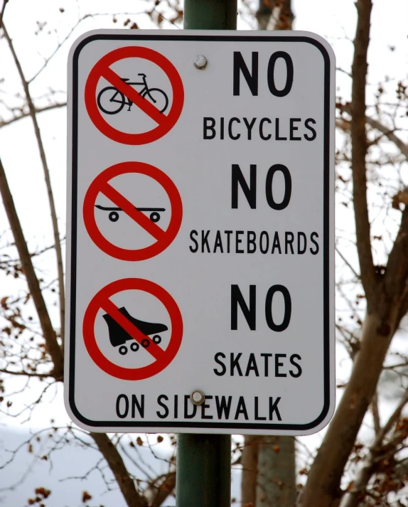 there are three signs on a post that show bicycles no skateboarding or skateboarding