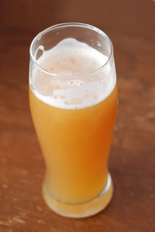 a cup filled with beer sitting on top of a wooden table