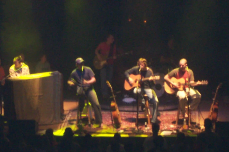 some men are singing and playing instruments on a stage