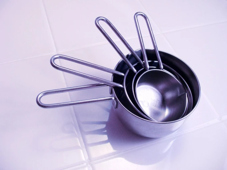 the four metal measuring cups are lined up